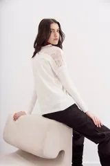 Remera color crudo de calce relajado y manga larga, con detalle de encaje en espalda y hombros.