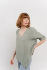 Blusa color naranja confeccionada en 100% lino, con escote en V, mangas cortas con vuelta y silueta amplia. Presenta terminación asimétrica y fila de botones decorativos en uno de los hombros.