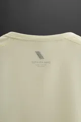 Camiseta deportiva de manga larga color amarillo pálido, confeccionada en tejido técnico perforado, ligero y elástico.