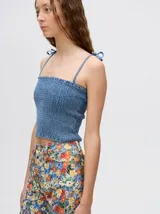 Top corto negro con textura fruncida, tirantes finos con lazos ajustables y corte crop.