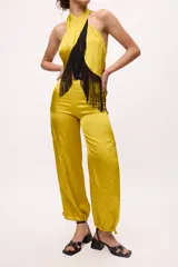 Top amarillo de satén con cuello halter y flecos negros.