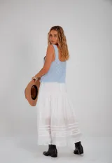 Falda larga blanca de estilo romántico, con volados en el ruedo y detalles de puntilla y encaje bordado.