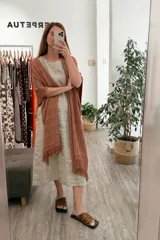 Ruana tejida color marrón terracota, con diseño calado de puntos y terminaciones con flecos.