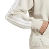 Campera con capucha Adidas Essentials 3S color gris claro, con cierre frontal, cordón ajustable, bolsillos canguro, puños y dobladillo acanalados, hombros caídos y las tres tiras blancas características de la marca en las mangas.