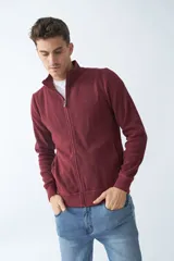 Campera marrón de algodón con cierre frontal, cuello alto, bolsillos laterales, puños y logo bordado en el pecho.