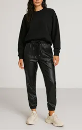 Pantalón babucha negro simil cuero, con cintura elastizada con cordón ajustable y bolsillos laterales.