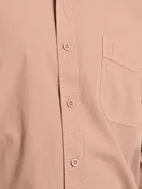 Camisa de manga larga color verde oliva, confeccionada en algodón. Tiene corte clásico, bolsillo en el lado izquierdo del pecho y cierre con botones.