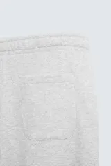 Pantalón jogger wide fit negro confeccionado en tejido de algodón con interior rizo. Pernera ancha, cintura elástica ajustable con cordón interior, bolsillos laterales y bolsillo trasero de plastrón.