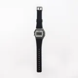 Reloj digital plateado con correa de caucho negra.