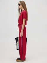 Pantalón de algodón negro, corte holgado y pierna ancha con pretina elástica. Presenta rayas bicolor al costado en blanco y celeste. Calce de tiro alto.