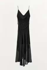 Vestido midi negro de tirantes finos con escote fluido y detalle de abalorios en el corpiño. Falda asimétrica con volados. Forro interior.