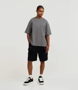 Bermuda masculina color negro de algodón y poliéster, con cintura ajustable mediante lazo, bolsillos cargo laterales con cierre de cremallera y bolsillos traseros.