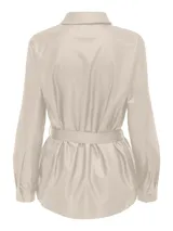 Camisa color beige de eco cuero con cuello clásico, cierre frontal con botones a presión, mangas largas con puños abotonados, dos bolsillos de parche en el pecho y cinturón de lazo en la cintura.