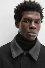 Parka negra de algodón con cuello solapa de cuero sintético, corte recto, acolchada y con cierre frontal de botones.