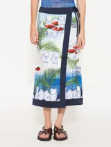 Pollera tipo portafolio de satén con estampado de palmeras, cubos de hielo y labios rojos. Tiene cinta para anudar en la cintura, botón interno y zócalo de tela complemento en cintura y ruedo.