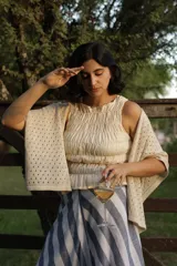 Ruana de tejido artesanal color beige, con diseño de puntos calados y mangas anchas.