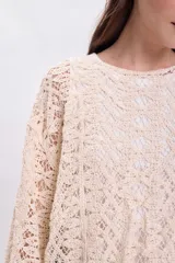 Sweater de crochet color crudo con mangas largas acampanadas.