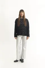 Sweater de punto calado color crema, con cuello alto y mangas largas.