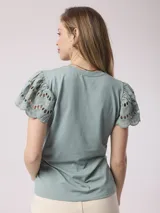 Remera blanca de poliéster y spandex con mangas cortas con volados de encaje.