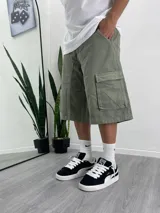 Bermuda verde militar de corte ancho, con bolsillos cargo laterales y traseros.