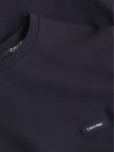 Remera azul marino de manga larga con cuello redondo y corte slim. Tiene un parche con el logo de Calvin Klein en el pecho.