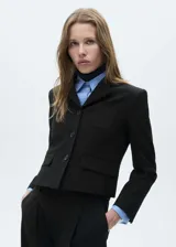 Blazer corto negro con cuello de solapa de pico, cierre frontal con botones y bolsillos de parche.