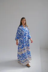 Vestido largo de corte holgado con estampado floral en tonos azul y blanco. Tiene cuello en V, mangas largas y falda con volantes.