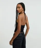 Top cropped de algodón color amarillo pálido, con escote en V pronunciado y tirantes finos que se atan en la nuca (estilo halter). El tejido es acanalado.