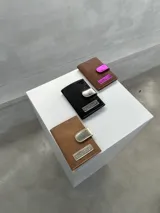 Porta pasaporte marrón con apliques plateados y cierre con broche.