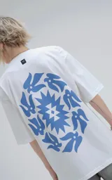Remera blanca de corte holgado con estampado azul de diseño geométrico y aves.