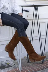 Botas texanas de caña alta color marrón, confeccionadas en gamuza, con puntera fina y taco cuadrado.