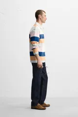 Polo de manga larga con cuello clásico y cierre de botones oculto. Diseño a rayas horizontales en colores azul, naranja, rosa y verde.