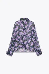 Camisa semitransparente de manga larga con estampado de flores color lila y cuello solapa. Presenta volantes en el frente y cierre con botones.