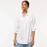 Camisa blanca de popelina, de corte holgado, con cuello clásico, cierre frontal con botones y mangas 3/4.