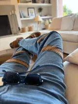 Pantalón de jean azul con corte holgado y apliques de gamuza marrón bordados a mano en los laterales.