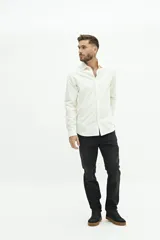 Camisa blanca de manga larga texturizada, tejida en dobby, con cuello italiano y cartera abotonada. Tiene un logo bordado en el pecho.