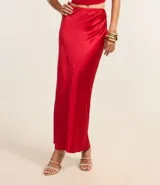 Vestido largo de satén color crema, con escote halter, espalda descubierta y abertura frontal. Presenta detalles de pedrería en el escote.