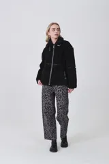 Campera de corderito color negro, con cuello alto y cierre frontal completo. Presenta detalles de vivos en cuero sintético en el cierre, bolsillos y costuras, además de una hebilla decorativa en el cuello.