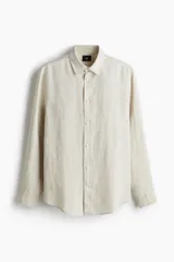 Camisa de lino color crema, de corte recto, con cuello inglés, tapeta clásica, mangas largas con puños abotonados y bajo redondeado.