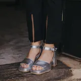 Sandalias de cuero color marrón con plataforma y tacón cuadrado. Tiras anchas sobre los dedos y tobillo con hebilla ajustable.