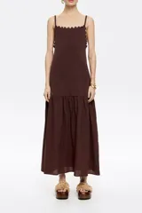 Vestido largo marrón de punto, con tirantes finos, escote recto con ondas y falda con vuelo.