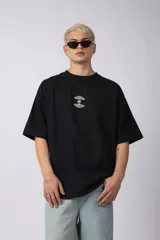 Remera negra oversize de algodón premium pesado, con bordado frontal de dos árboles unidos por sus raíces y parche estampado en la espalda con una silueta de mano que se fusiona con ramas.