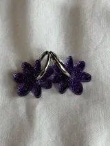 Aros colgantes plateados con dije de flor acrílica color dorado.