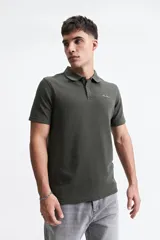 Polo verde militar con textura, corte regular y logo bordado en el pecho.