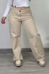 Pantalón de jean color beige, estilo baggy o wide leg, de tiro medio, con cierre de botón y cremallera.