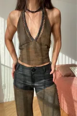 Top marrón de cuero ovino vintage con cuello halter y espalda descubierta. Presenta detalle artesanal de cutouts y pasamanería en negro alrededor del cuello y lazos finos negros para atar en el frente.