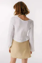 Blusa blanca de lino con escote en V, mangas largas abullonadas y frunce central.