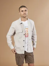 Camisa beige de manga larga con dos bolsillos frontales con solapa y cierre de botones.