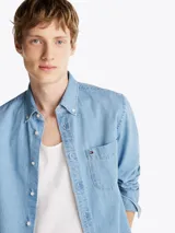 Camisa de denim celeste de Tommy Hilfiger de corte regular, con cuello abotonado, manga larga con puños abotonados, bolsillo de parche en el pecho y logo bordado en el bolsillo.