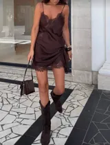 Vestido corto marrón de satén con encaje en escote, breteles y ruedo. Diseño asimétrico.